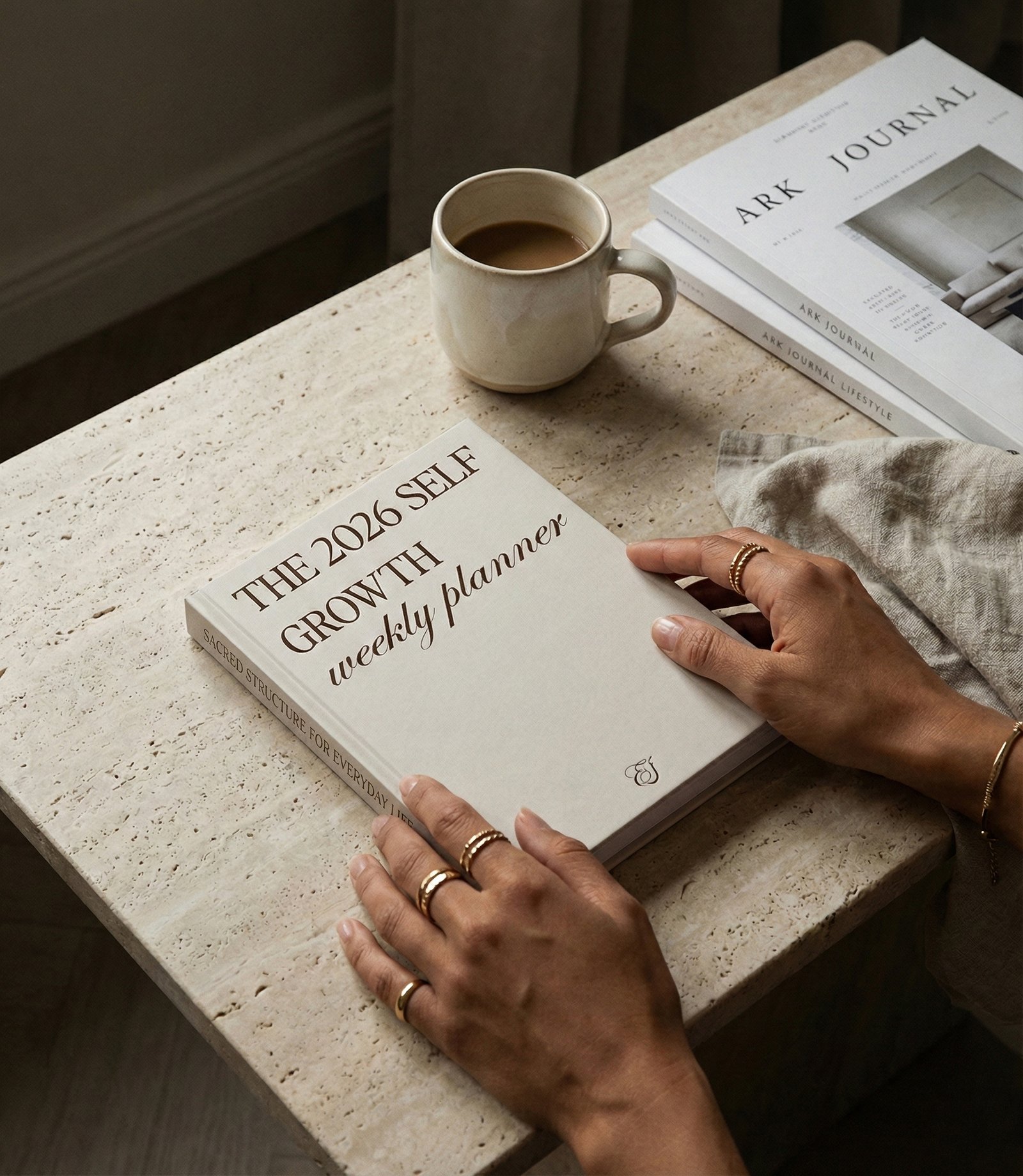 The 2026 Self Growth Weekly Planner by Ellafits. A modern, editorial-style planner with a hard cover in a Cream tone and elegant gold typography that reads 'THE 2026 SELF GROWTH weekly planner'. Ideal for strategic organization and personal growth. This planner is on a table with a woman around in a minimalistic mood